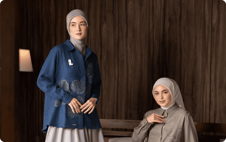 Two women in modest outfits against dark wood panelling, one in a blue denim shirt and one in soft khaki, each in her own personal style in modest fashion